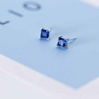 сребърни обеци със син скъпоценен камък, снимка на син фон