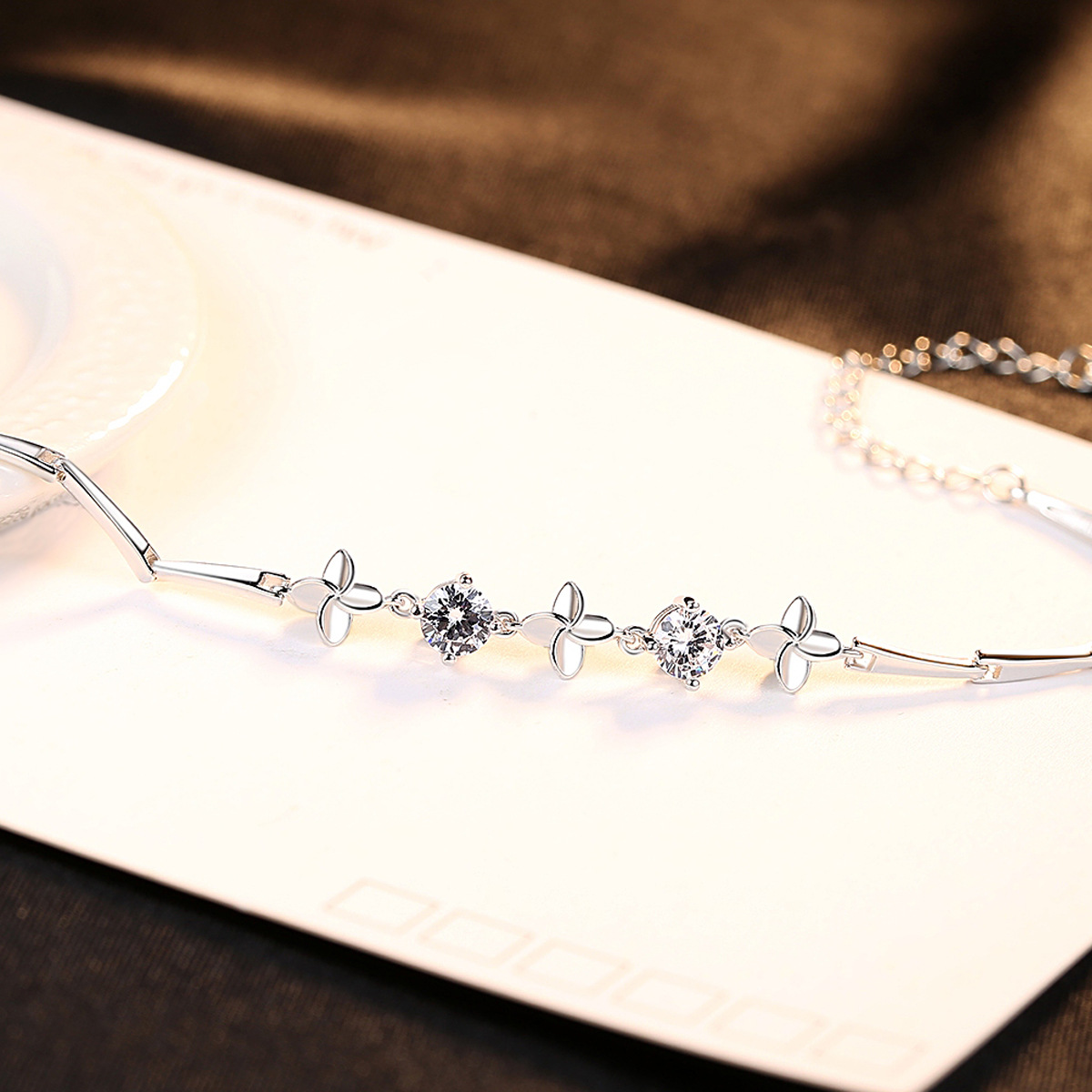 Сребърна гривна - Виждане - Сребърен гривна с блестящи камъни, снимка на жълт фон Сребърен гривна с блестящи камъни, снимка на жълт фон