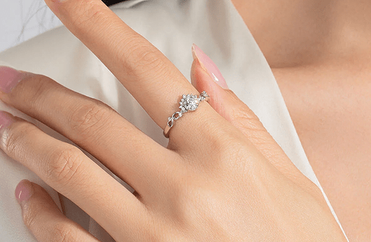 srebaren-prasten Сребърен пръстен с кристали и флорален дизайн, носен на безименен пръст на жена с маникюр.